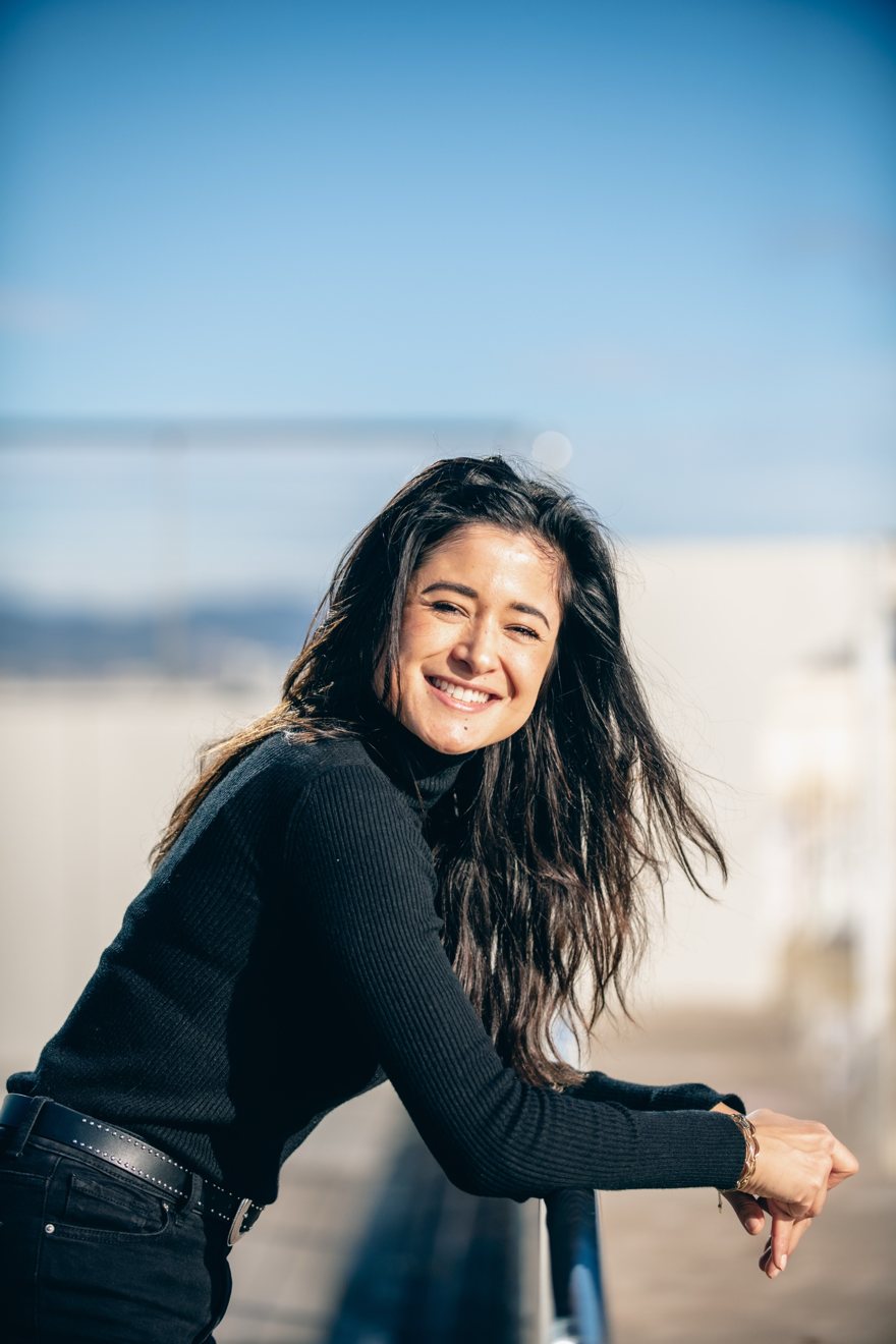 Elise, co-founder of Traitly, smiling and leaning on a railing in the sun